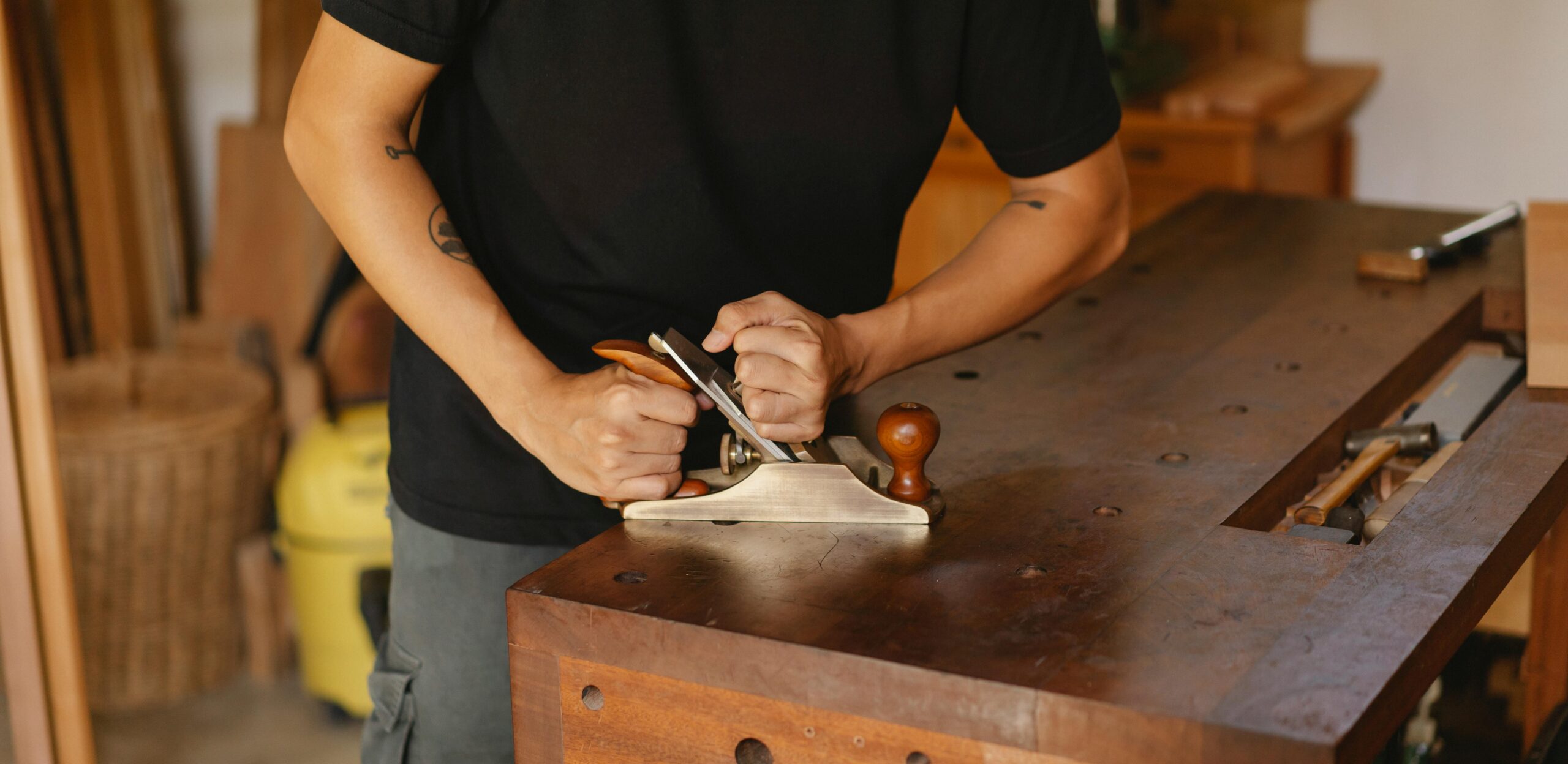 Woodworker focuses on smoothing wood with a planer in a cozy workshop setting.